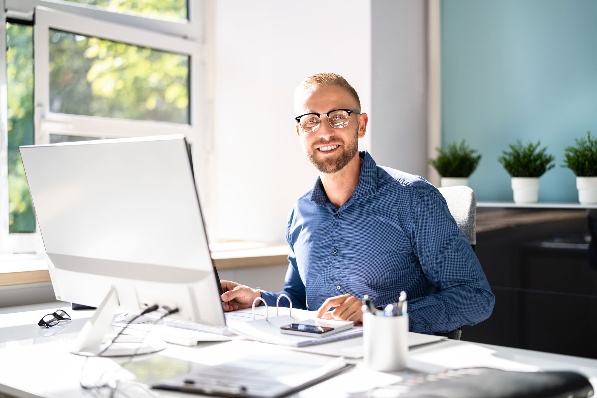 Ein Bestatter im Büro nutzt die Ruhe Sanft Bestattungssoftware und lächelt
